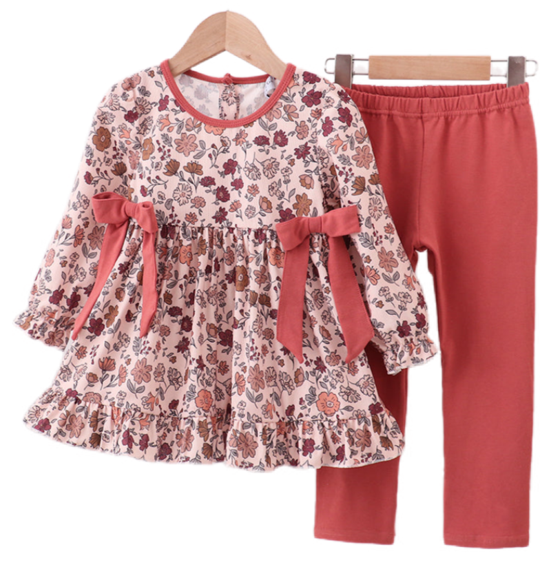 Two baby girl autumn outfits in soft corduroy with warm floral prints. One is a romper with ribbon details, and the other is a pants and top set, both in matching fall tones.